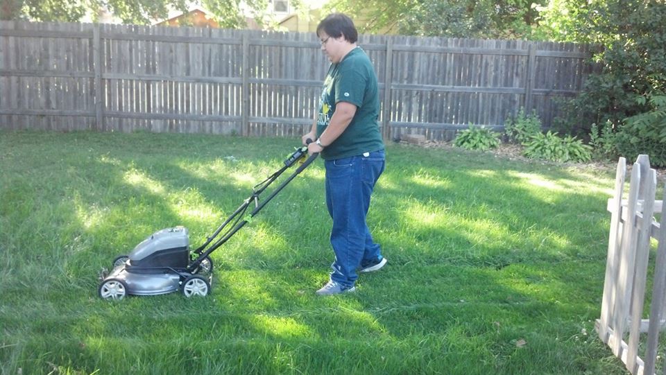 Me pushing a lawnmower in a backyard